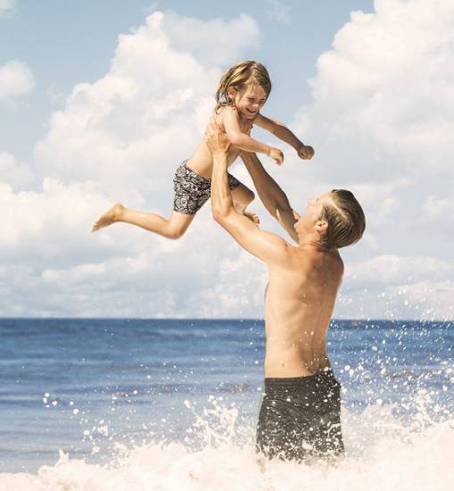 Dad playing at the beach with their kid.